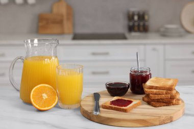 Kahvaltı mutfakta servis edilir. Çıtır tost, reçel ve portakal beyaz masada taze.