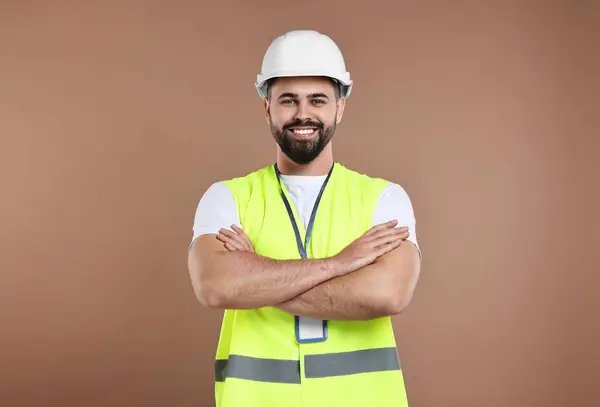 Engineer with hard hat and badge on brown background