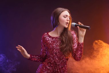 Mikrofonlu duygusal kadın renk ışıklarıyla şarkı söylüyor