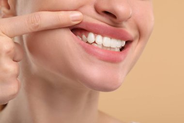 Bej arka planda temiz dişlerini gösteren kadın, yakın plan.