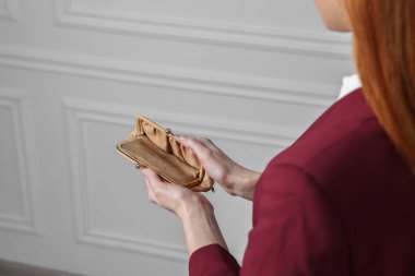 Beyaz duvarın yanında cüzdanı boş bir kadın, yakın plan.