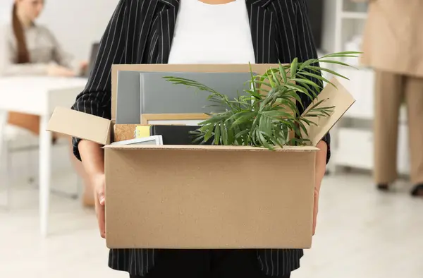 Unemployment problem. Woman with box of personal belongings in office, closeup