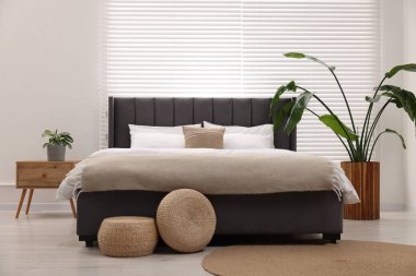 Şık bir yatak odasında büyük bir yatak ve bitkiler. İç tasarım