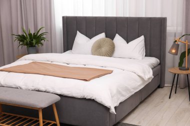 Şık bir yatak odası. Büyük yatak odası, kanepe, lamba ve çiçek.