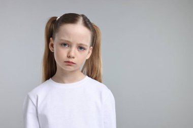 Açık gri arkaplanda üzgün bir kızın portresi, metin için boşluk