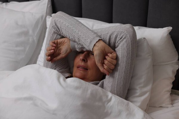 Menopause, sleep problems. Woman suffering from insomnia in bed