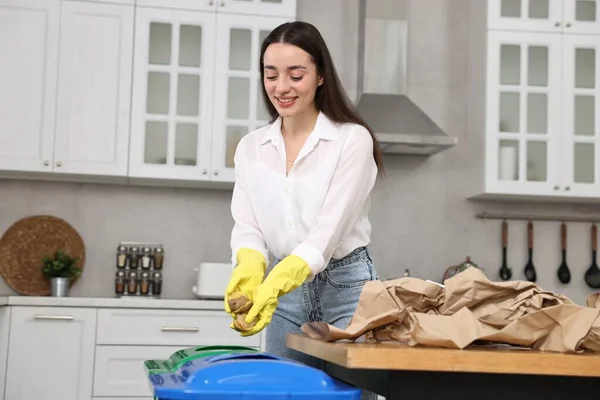 Garbage sorting. Smiling woman throwing potato peel into trash bin in kitchen