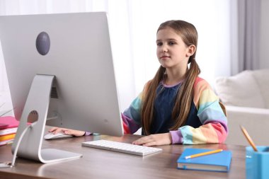 E-öğrenme. İçerideki masada çevrimiçi ders sırasında bilgisayar kullanan sevimli kız.