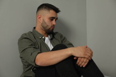 Açık gri duvarın yanındaki üzgün adamın portresi