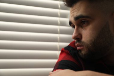 Kapalı panjurların yanındaki üzgün genç adam. Metin için boşluk