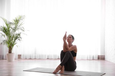 Genç bir kadın yoga stüdyosunda kartal asana alıştırması yapıyor. Garudasana pozu