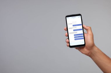 Arkadaşlarıyla mesajlaşan bir adam akıllı telefondan gri arkaplana mesaj yolluyor, yakın plan. Metin için boşluk