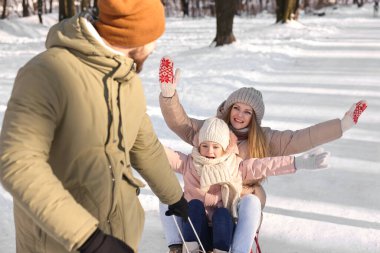 Mutlu aile karlı ormanda balyozla eğleniyor.