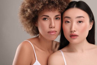 Gri arka planda sağlıklı cilde sahip güzel genç kadınlar.