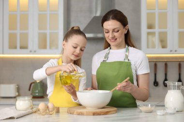 Ekmek yapıyorum. Anne ve kızı mutfaktaki beyaz masada hamur hazırlıyorlar.