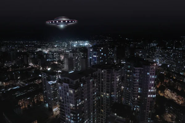 Uzaylı uzay gemisi gece şehrin üzerinde uçuyor. UFO, dünya dışı ziyaretçiler.