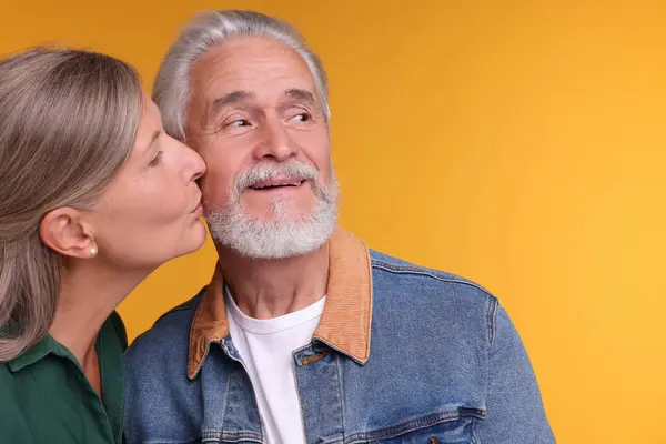 Senior Mulher Beijando Seu Amado Homem Fundo Laranja Espaço Para — Fotografia de Stock