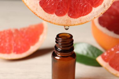 Temel yağ, arka planda hafif arkaplanda greyfurttan şişeye damlıyor.