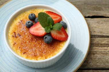 Böğürtlenli ve nane şekerli nefis creme brulee ahşap masada, üst tarafta.