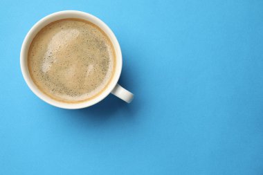 Açık mavi arka planda, fincanda Aromatik kahve, üst manzara. Metin için boşluk