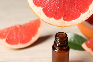 Temel yağ, arka planda hafif arkaplanda greyfurttan şişeye damlıyor.