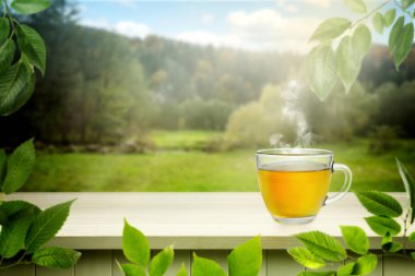 Açık ahşap masa üzerinde cam fincanda yeşil çay, metin için yer