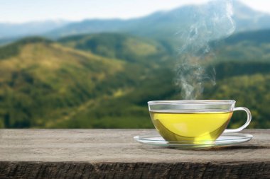 Dağlardaki ahşap masanın üzerinde cam fincanda yeşil çay, metin için yer