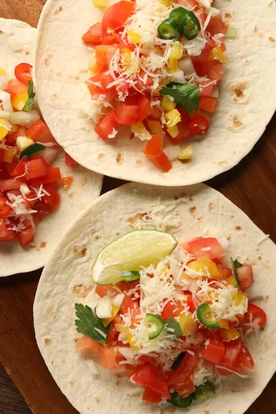 Sebzeli lezzetli tacolar ve ahşap masada limon, üst manzara.