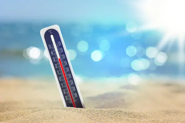 Thermometer on beach showing high temperature during summer day