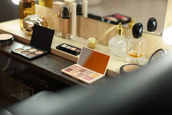 Makeup room. Cosmetic products and perfumes on wooden dressing table indoors