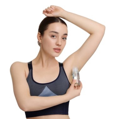 Güzel bir kadın beyaz arka plana deodorant sürüyor.