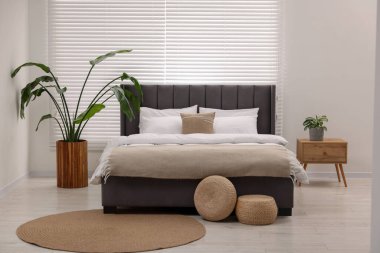 Şık bir yatak odasında büyük bir yatak ve bitkiler. İç tasarım