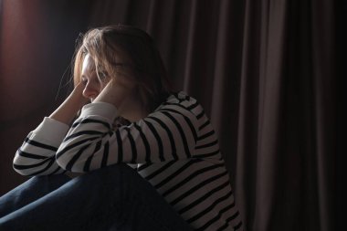 Perdelerin yanındaki üzgün genç kadın, mesaj için yer.