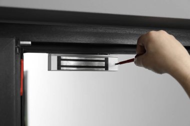 Tornavidalı bir adam elektromanyetik kapı kilidi yerleştiriyor, yakın plan. Ev güvenliği