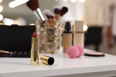 Makyaj odasındaki beyaz masaya kırmızı ruj ve diğer kozmetik ürünleri, seçici odaklanma