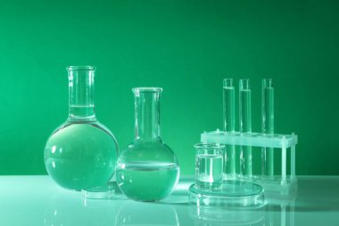 Laboratuvar analizi. Masada yeşil arkaplana karşı farklı cam eşyalar