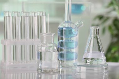 Laboratuvar analizi. Kapalı alandaki beyaz masa üzerinde sıvı bulunan farklı camlar.