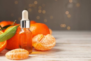 Bir şişe mandalina yağı ve beyaz ahşap masada taze meyveler, yakın plan. Metin için boşluk