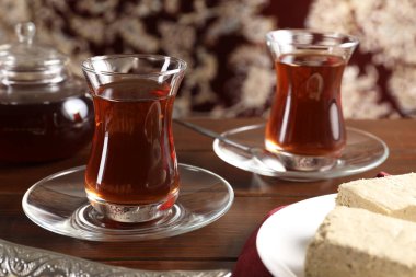 Kadehli geleneksel Türk çayı ve ahşap masada lezzetli halva, yakın plan.