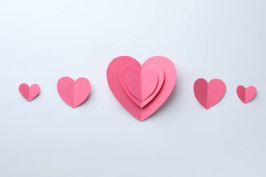 Beyaz zemin üzerinde pembe kağıt kalpler, düz uzanmış