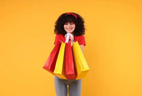 Sarı Arka Planda Alışveriş Torbaları Olan Mutlu Genç Bir Kadın — Stok fotoğraf