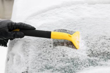 Arabanın ön camından kar temizleyen adam, yakın plan.