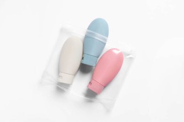 Beyaz arka planda plastik poşet içinde kozmetik seyahat kiti, üst görünüm