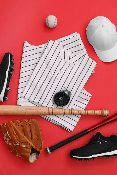 Flat lay composition with baseball uniform and sports equipment on red background