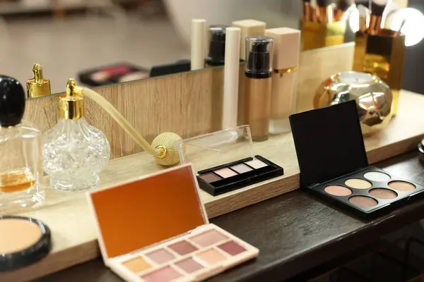 Makeup room. Cosmetic products and perfumes on wooden dressing table indoors