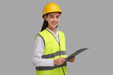 Gri arka planda elinde pano tutan sabit şapkalı mühendis.