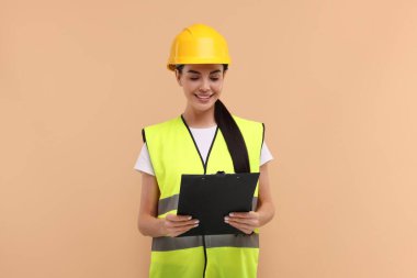 Kask takan mühendis bej arka planda pano tutuyor.