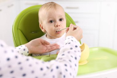 Anne, küçük bebeğini sağlıklı yiyeceklerle besliyor.