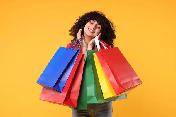 Sarı Arka Planda Alışveriş Torbaları Olan Mutlu Genç Bir Kadın — Stok fotoğraf