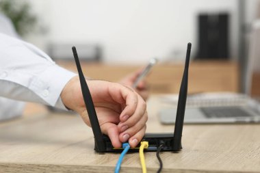Adam kabloyu Wi-Fi yönlendiricisine yerleştiriyor. Kapalı masa, yakın plan.